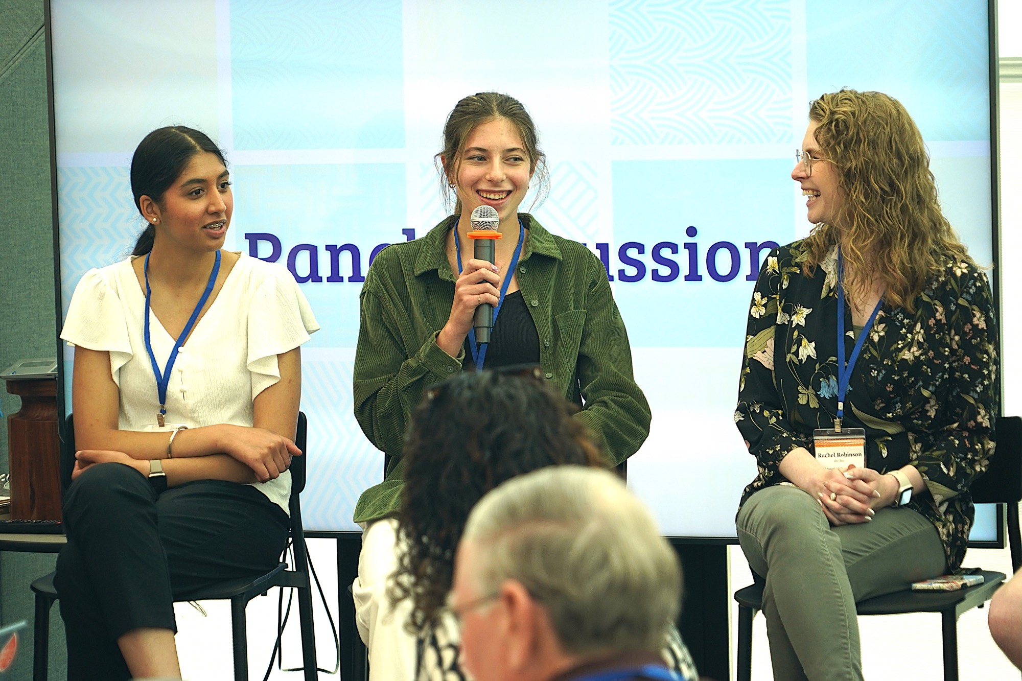 Three panelists, one with a microphone